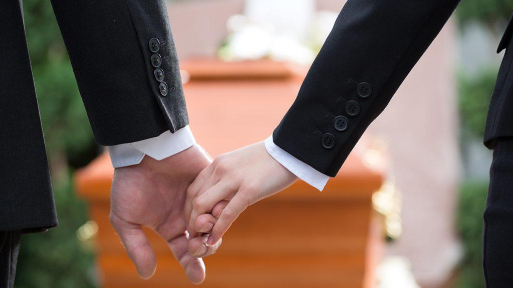 A couple at funeral holding hands consoling each other in view of the loss.