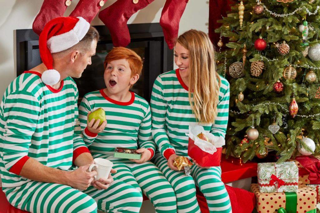 A photo of gift giver with a family on Christmas morning opening presents.