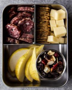 Road trip snack box with cheese, fruit, meat, and crackers.