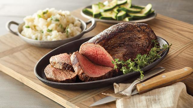 Chateaubriand on a platter with side dishes.