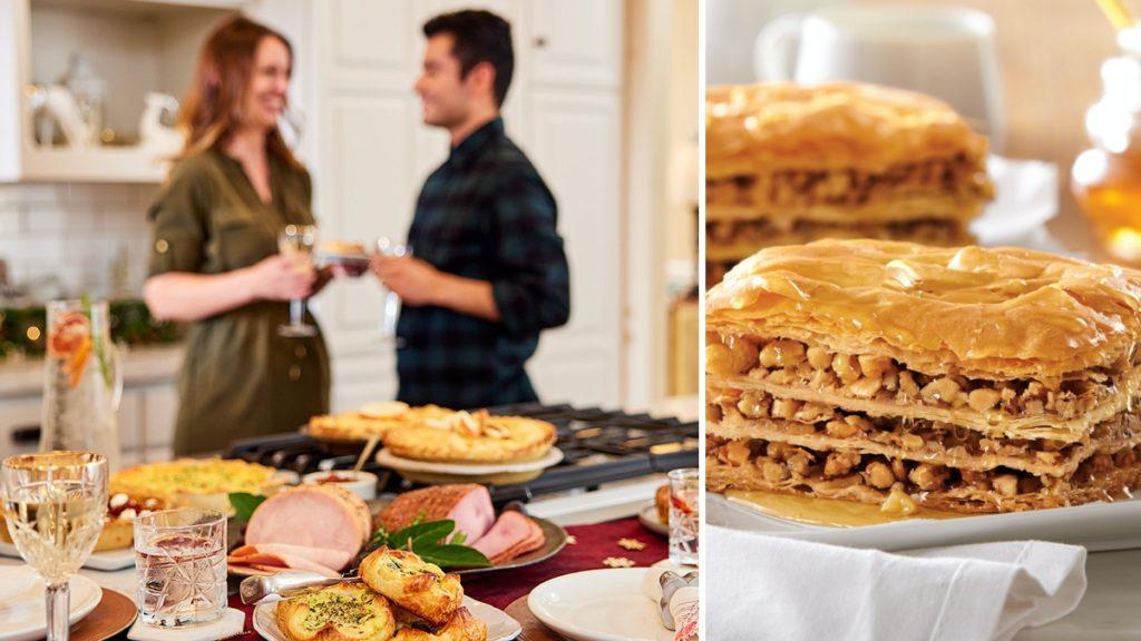 A photo of Thanksgiving dinner with a couple talking in the background with food on a counter including baklava