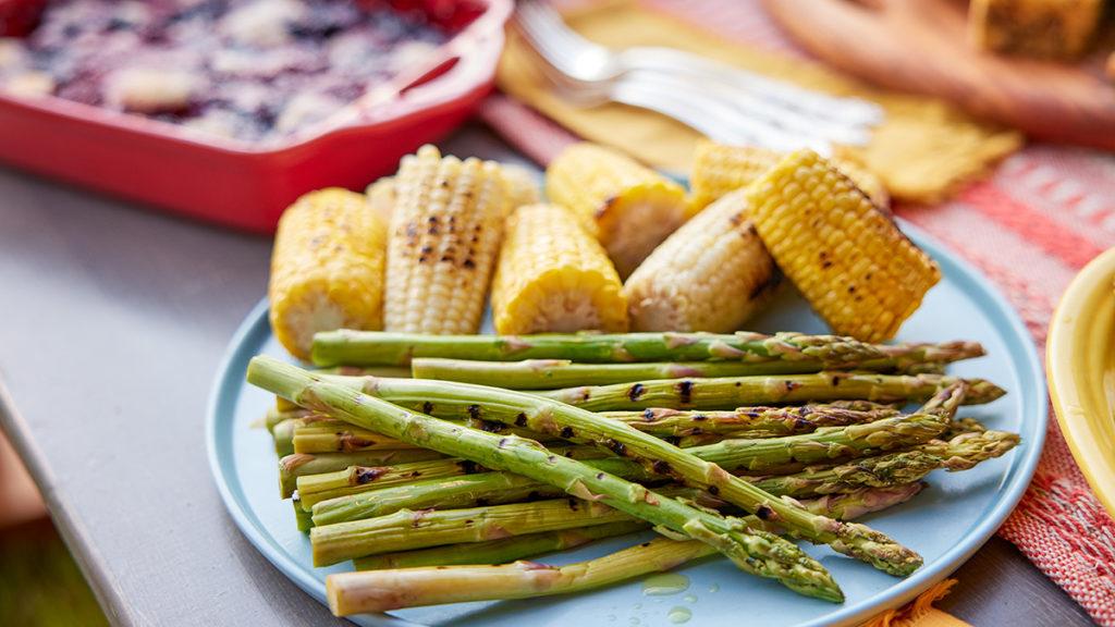 Photo of how to grill with a plate full of grilled asparagus and corn.