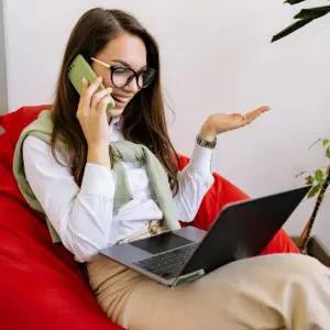 Office superstars with a woman sitting with a laptop on her lap and talking on the phone